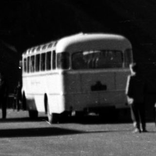 Vintage cars and bus on snowy mountain road.