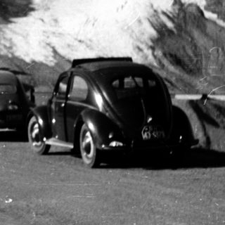Vintage cars and bus on snowy mountain road.