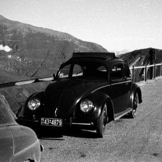 Classic car near mountain tunnel entrance.