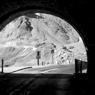 Tunnel exit revealing mountainous road ahead.