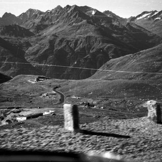 Mountainous landscape with road and small structures.