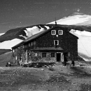 Mountain hut surrounded by snow-covered landscape.