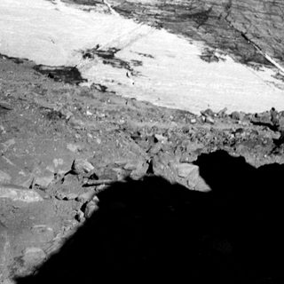 Barren rocky terrain near glacier edge.