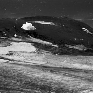 Black-and-white aerial view of snow-capped volcanic terrain.
