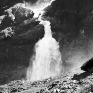 Powerful waterfall cascading down rocky mountain terrain.