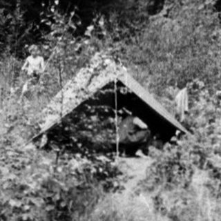 Campsite with tents and hikers carrying supplies.
