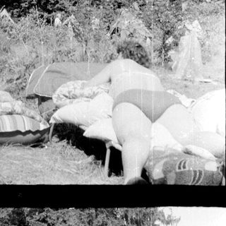 Campsite scene with tents and people relaxing outdoors.