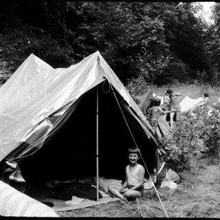 Campsite with tents and people outdoors.