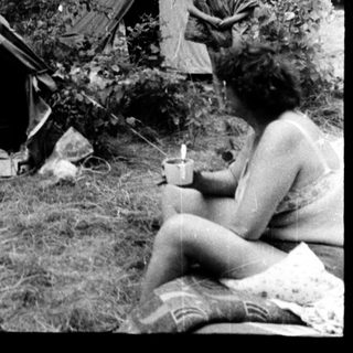 Campsite with tents and people relaxing outdoors.
