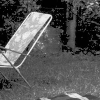Shirtless boy sitting outside on left, backyard scene with umbrella and chairs.