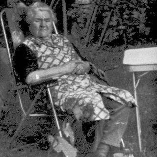 Shirtless boy sitting outside on left, backyard scene with umbrella and chairs.