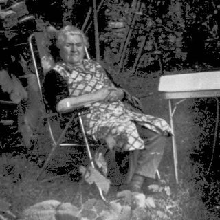 Shirtless boy sitting outside on left, backyard scene with umbrella and chairs.