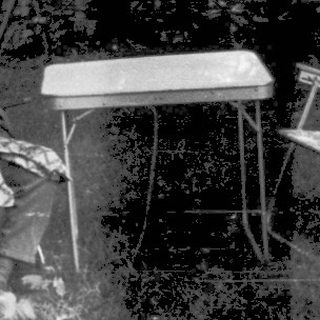 Shirtless boy sitting outside on left, backyard scene with umbrella and chairs.