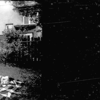 Blurred nighttime courtyard with person lying on blanket.