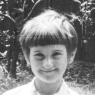 Young boy holding small bird outdoors.