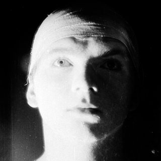 Young man with bandaged head, serious expression.