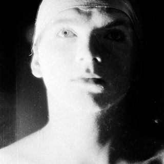 Young man with bandaged head, serious expression.