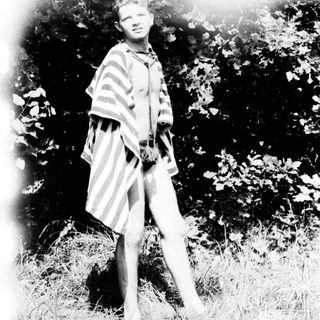 Young person in vintage striped dress standing outdoors.