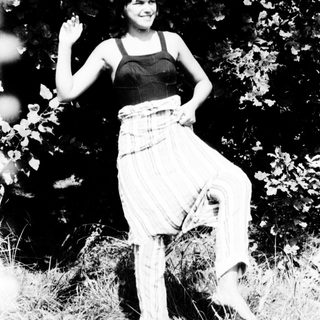 Woman posing casually in outdoor grassy area.