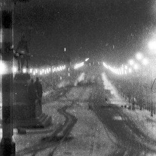 Empty, snow-covered street lit by streetlights.