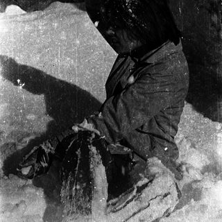 Person sitting on rocky ground near fire.