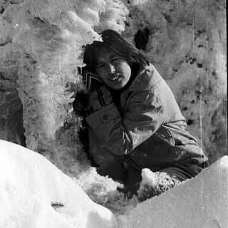 Person sitting in snow-covered rock crevice.