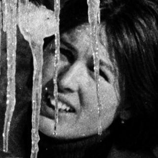 A person smiling in winter, surrounded by icicles.