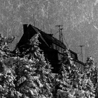 Snow-covered forest with ski lift and building.