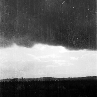 Dark sky with dramatic vertical light streaks, illuminating storm clouds over distant landscape.