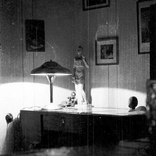 Vintage bedroom scene with statue, desk lamp, and framed art.