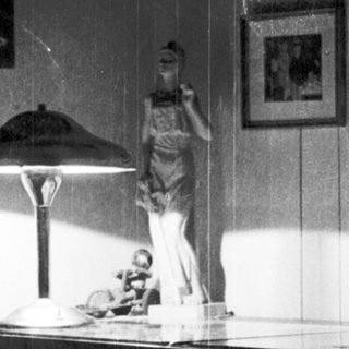 Vintage bedroom scene with statue, desk lamp, and framed art.