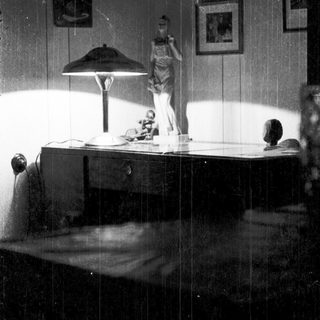 Vintage bedroom scene with statue, desk lamp, and framed art.