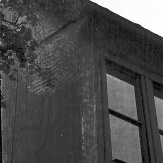 Weathered stone building facade with aged window.
