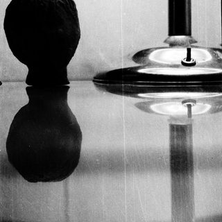 Black chess piece on reflective surface.