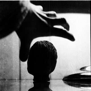 A hand holding a chess piece near a mirror.