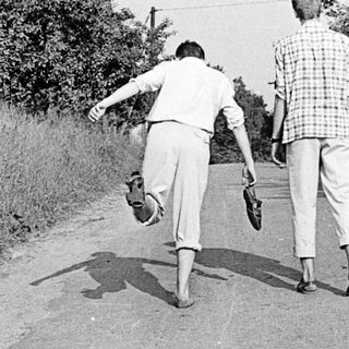 Two men playing frisbee on a rural road.