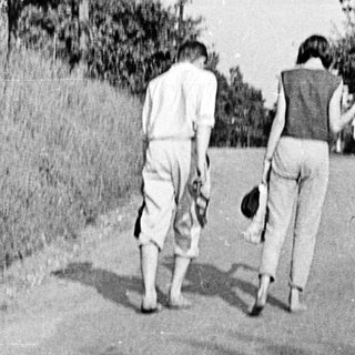 Two individuals walking away on a rural road.