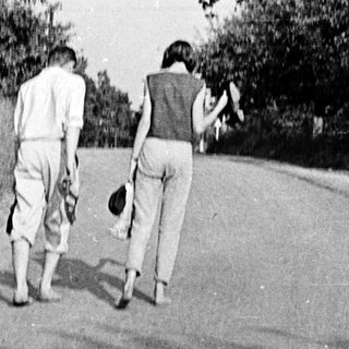 Two individuals walking away on a rural road.