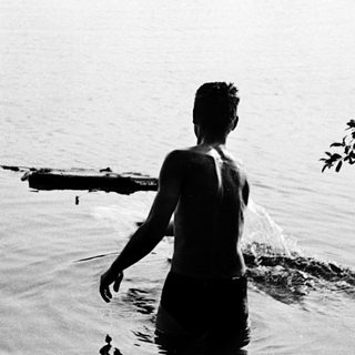 Man standing in shallow water by lake.