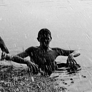 Two people swimming in rain-soaked water.