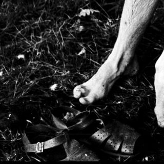 Two individuals holding hands, barefoot on grass.