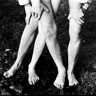 Two individuals holding hands, barefoot on grass.