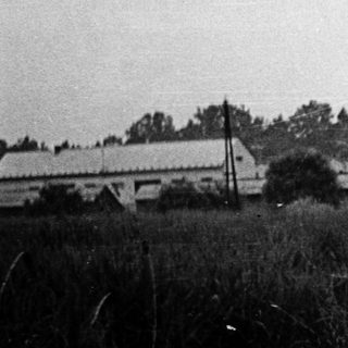 Rural landscape with pond, buildings, and trees.