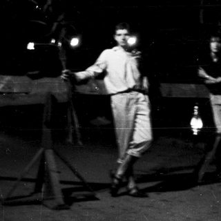 Two men performing with lanterns in dark setting.