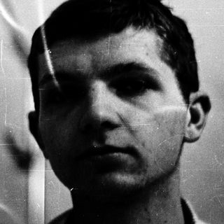Young man in black-and-white portrait with blurred background.
