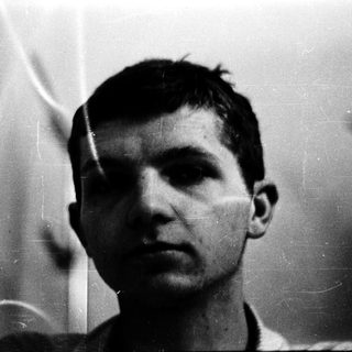 Young man in black-and-white portrait with blurred background.