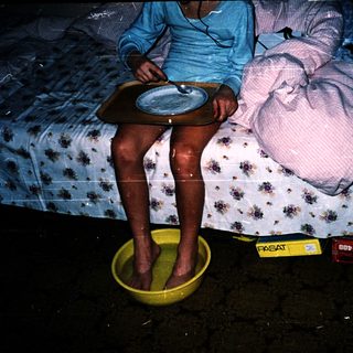 Person sitting on bed with feet in water basin.