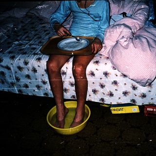 Person sitting on bed with feet in water basin.