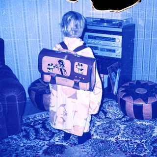 Child wearing backpack and pajamas near stereo equipment.