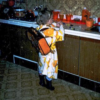Child in colorful dress examining kitchenware display.